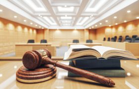 Interior of an empty courtroom with gavel, law books and sounding block on the desk.